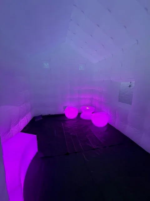 Inside a white inflatable party tent lit purple with LED seats